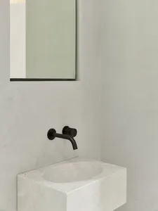 Modern bathroom featuring a minimalist white marble sink with a black faucet and a rectangular mirror on the wall.