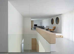Modern living room with concrete floor, glass walls, and wooden furniture.