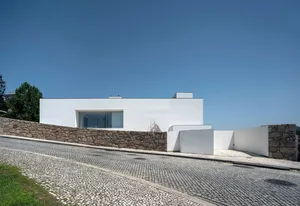 一間極簡住宅，擁有混凝土牆，位於鵝卵石街道上。