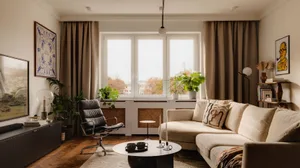 A modern living room with neutral-tones furniture, plants, and a large window.