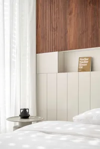 Minimalist bedroom featuring a wooden headboard, white curtains, and a white bed.