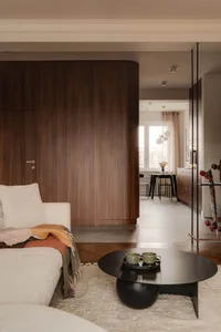 A minimalist living room with a white sofa, wooden walls, and black coffee table.
