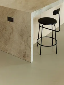 Modern kitchen counter with a marble surface and a black stool next to it.