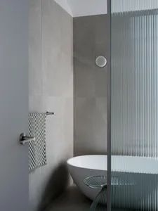 A modern bathroom with grey tiled walls, a freestanding bathtub, and a sleek shower enclosure.