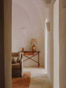 A minimalist living room with a wooden table, beige couch, and beige lampshade.