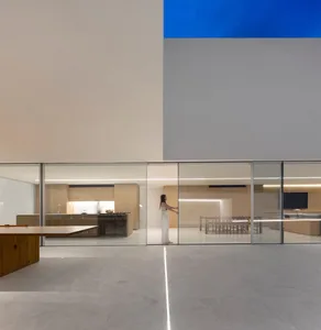 A spacious, modern house interior featuring glass walls and concrete floors.