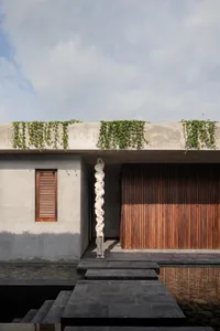 A modern exterior building facade with a plant wall on the rooftop and concrete steps.