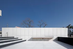 Modern minimalist architecture with concrete walls and steps, featuring a concrete bench and minimalist design elements.