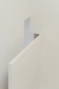 A minimalist hallway with white walls and a white staircase.