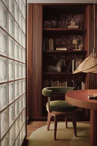 A well-designed home office featuring wooden shelving and a round wooden table with a green cushioned chair.
