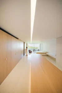 A modern minimalist bedroom featuring wooden flooring and a glass wall with a view.