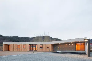 Modern house with wooden and concrete exterior and large glass windows.