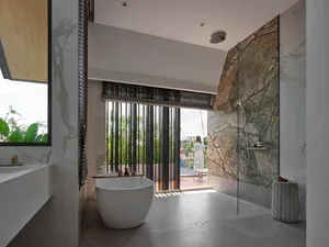 Modern bathroom with marble and concrete finishes, featuring a freestanding bathtub and a walk-in shower.