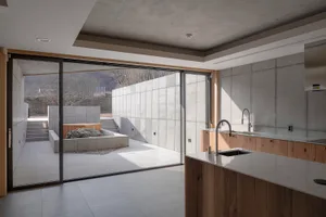 A modern kitchen with a minimalist design featuring concrete walls and flooring.