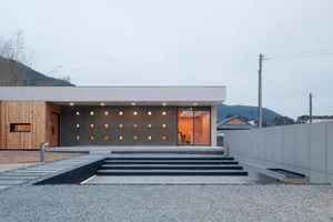 Modern house exterior featuring concrete and glass walls, with a minimalist design and bright sunlight.