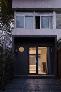 Modern, minimalist residential entryway with a concrete facade and large glass window.