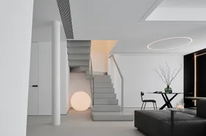 A modern, minimalist living room with sleek, white furniture and a gray sofa, illuminated by a spherical lamp and ambient lig