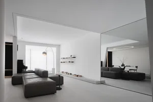 A modern minimalist living room with concrete flooring, black furniture, and a floor lamp.