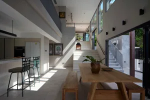 Modern minimalist residential interior featuring wood dining table and concrete floor.