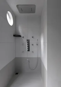 A minimalist white bathroom with modern fixtures and a circular window.