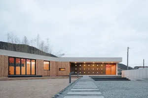 Modern residential house with wooden siding and large windows.