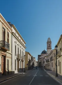 A picturesque old town street view with historic buildings and a cathedral in the distance.