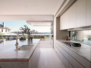 Modern industrial kitchen with marble countertops, steel appliances, and glass walls.