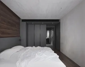 A minimalist bedroom with a concrete wall and a creased white duvet on the bed.