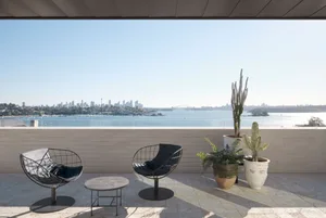 Modern minimalist outdoor lounge area featuring concrete furniture and a panoramic view of a city skyline and waterfront.
