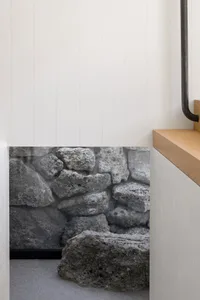 Modern interior space featuring a prominent stone wall made of large, rough-hewn concrete blocks.