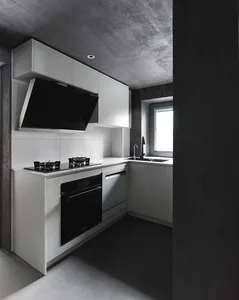 A modern kitchen featuring a minimalist design with white cabinets and concrete countertops.