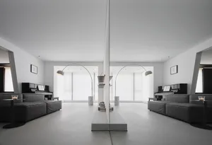 Modern minimalist living room with concrete floor, white walls, and black furniture.