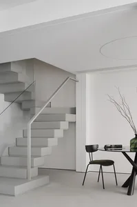 A minimalist interior space featuring a modern staircase with glass and metal elements.