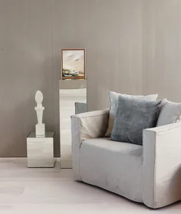 A modern living room with neutral-toned decor, featuring a comfortable armchair, a small side table with a glass tabletop, an