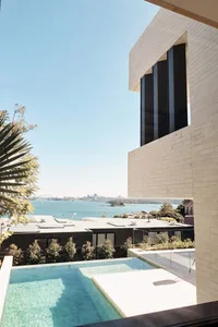 Modern residential exterior featuring cliff-side apartments with glass and stone materials.