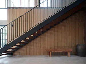 A modern hallway featuring a wooden bench and a steel and wood staircase.