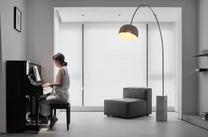 A minimalist living room with white walls, a black piano, and a gray couch.