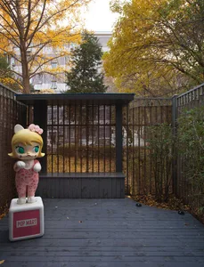 A wooden panel with a mascot installation in a garden setting, featuring a character with yellow hair and green eyes.