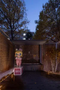 A wooden retail space with a large, colorful mascot statue outdoors at dusk.