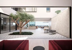 A modern living room with concrete walls and floor, featuring a tree in the center and a view of the city.