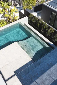 Modern swimming pool made of concrete and marble with a glass barrier.