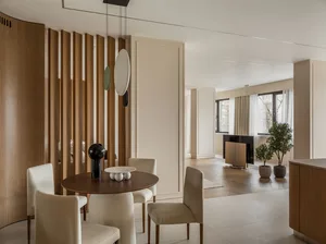 Modern dining room featuring wooden furniture and white chairs around a round wooden table.
