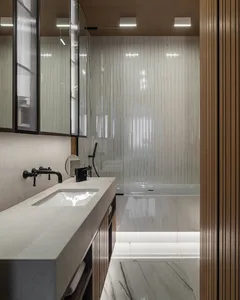 Modern bathroom with marble finishes, featuring a minimalist design with sleek, white fixtures and a large, textured glass sh