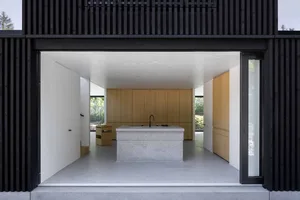 A modern kitchen with a concrete island and wooden cabinets.