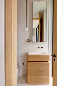 Modern minimalist bathroom with a wooden sink and tiled walls and floor.