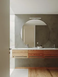 Modern minimalist bathroom featuring a concrete wall and floating vanity with wooden drawers.