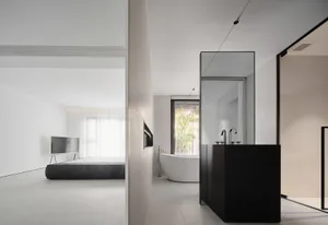 A minimalist interior design featuring a white concrete floor, black furnishings, and a modern bathroom setup.