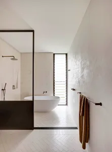 Modern bathroom featuring a white tiled floor and a white freestanding bathtub.