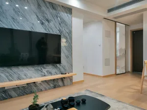 A modern living room featuring a black marble wall with a mounted flat-screen TV and a sleek coffee table with blue tea cups 