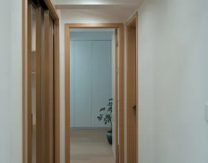 A minimalist corridor with wooden walls and doors, featuring a single plant.